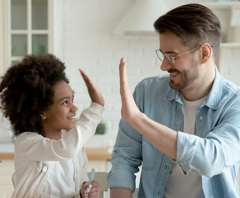A young black child high fives a white male for positive reinforcement.