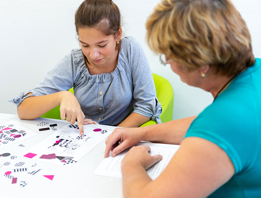 A behavior technician works with a teenage girl.